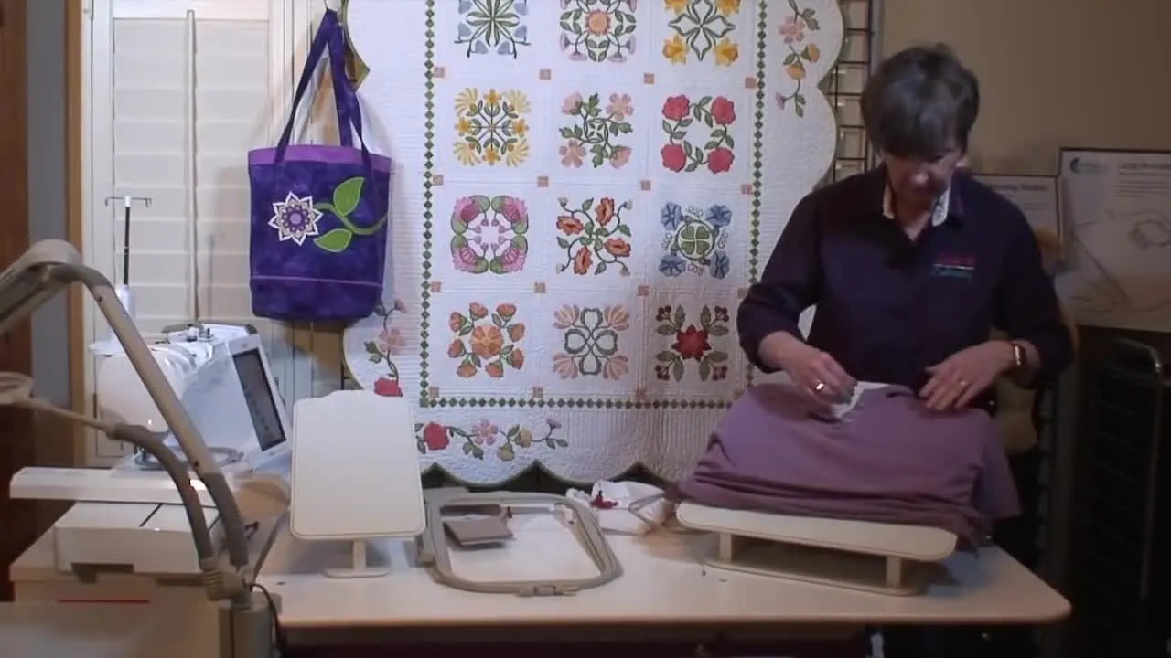 A purple women’s knit shirt is slid smoothly over the Echidna Hooping Station board, showing how the board separates garment layers for clean hooping.