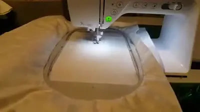 Close-up of the Brother Innov-is 2600 stitching the redwork-style snowmen outline on white snowflake fabric.