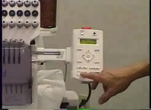 A wide view of a Happy multi-needle embroidery machine tracing the design boundary on hooped fabric before stitching.