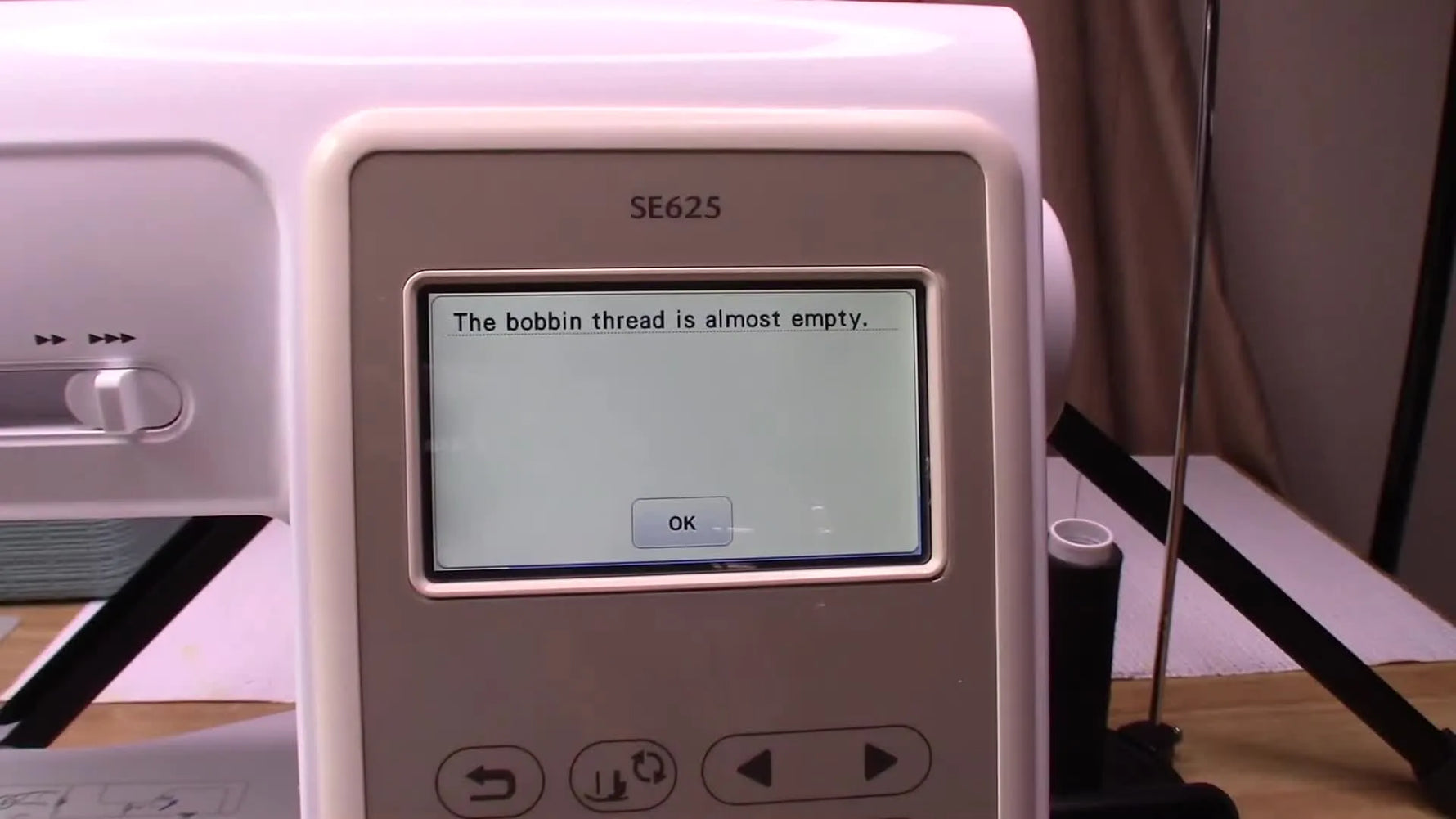 Close-up of the Brother SE625 LCD pop-up that reads “The bobbin thread is almost empty,” right as the machine stops and beeps.