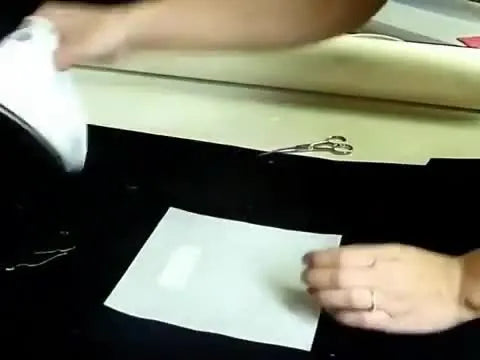A close-up of a household iron pressing from the back side of the substrate to permanently fuse a heat-seal patch without scorching the crest face.