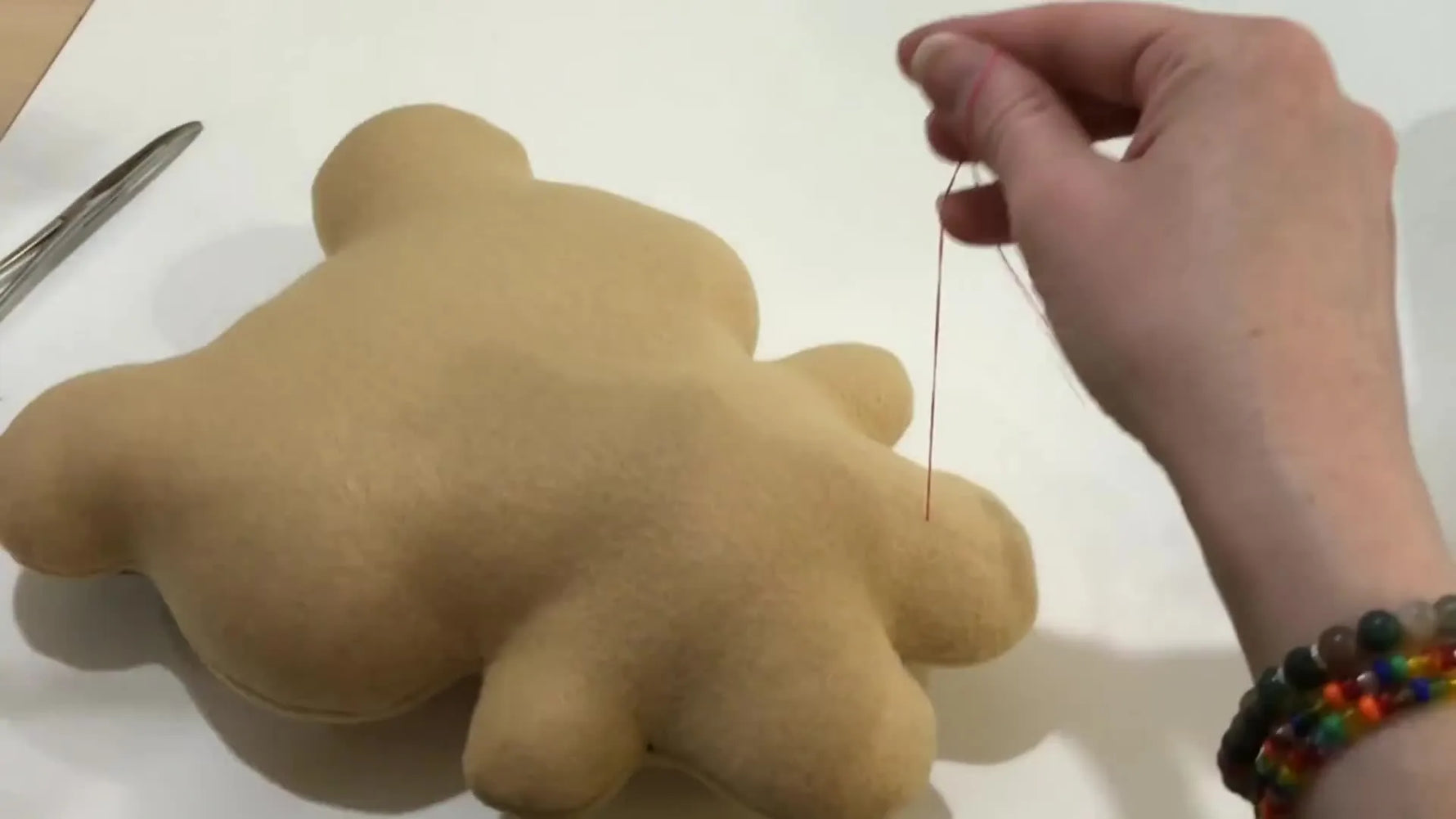 A finished kawaii-style in-the-hoop teddy bear stands upright, showing clean facial stitching and smooth seams.