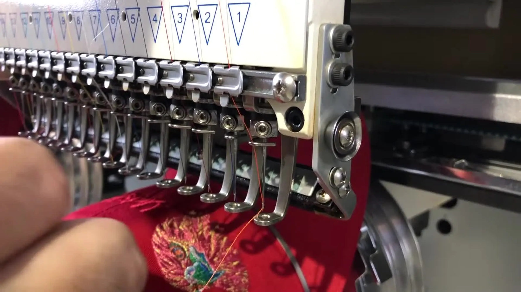 A close-up overview of the Meistergram needle case showing tension knobs, thread break wheels, and the embroidery head layout.