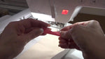 Pink embroidery tape securing the edges of the cream fabric to the stabilizer inside the hoop.