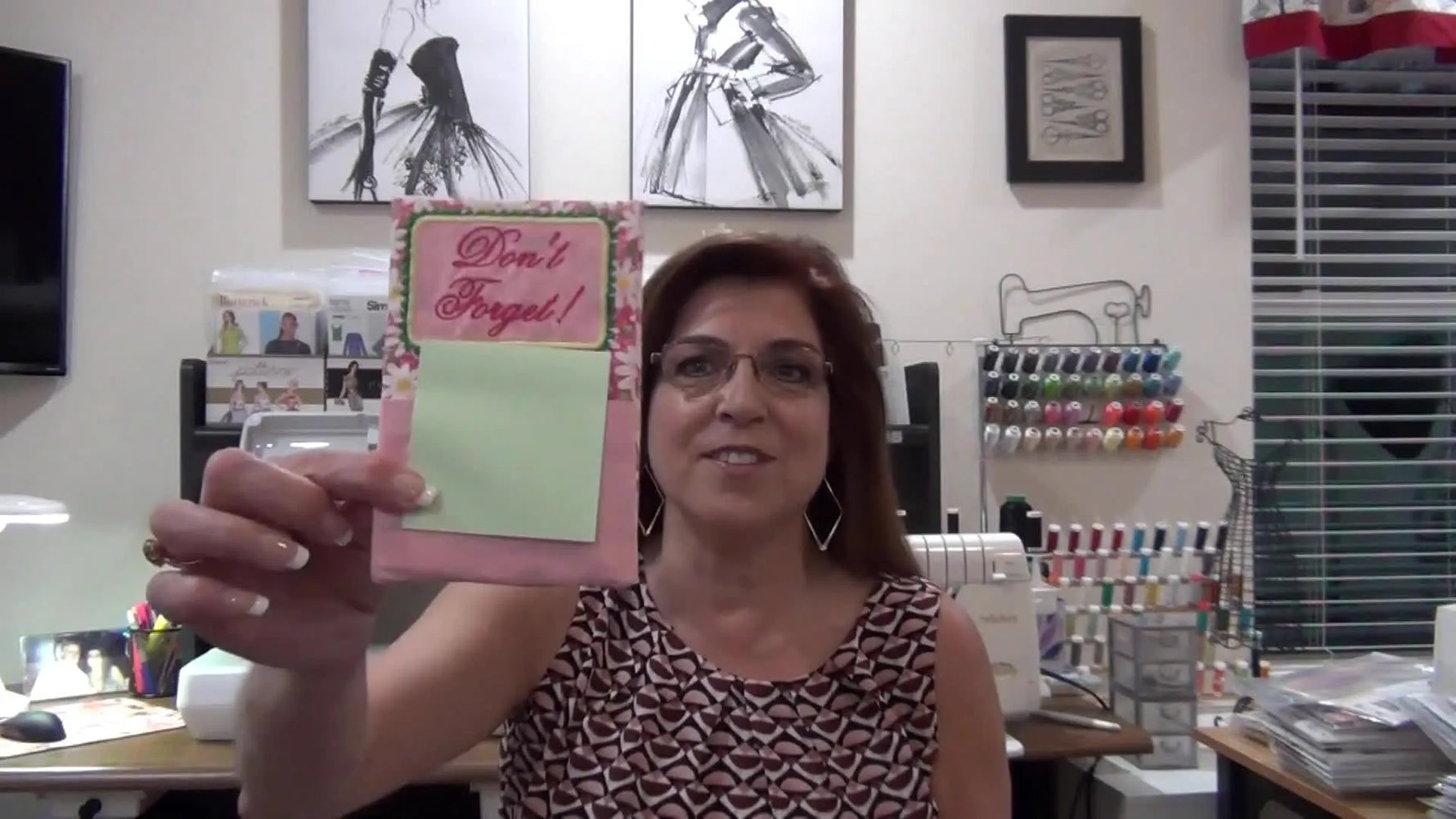 Grace holding up the finished pink vertical Post-It note holder with 'Don't Forget' embroidery.