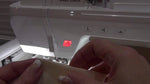 Aligning the folded cream fabric piece against the stitched placement line on the stabilizer.