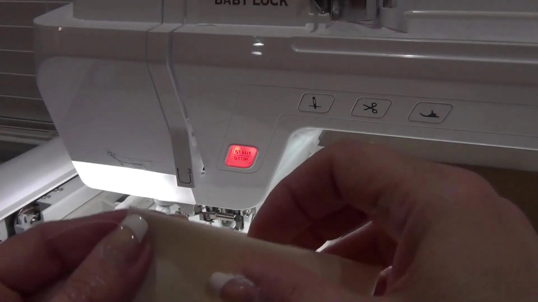 Aligning the folded cream fabric piece against the stitched placement line on the stabilizer.