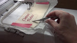 Using curved embroidery snips to trim jump stitches between letters.
